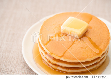 Delicious hot cakes drizzled with maple syrup 117449839