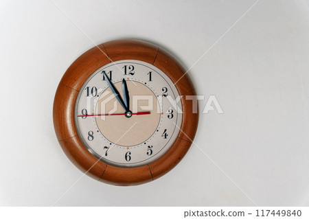 A classic wooden wall clock shows the time around nine o'clock 117449840