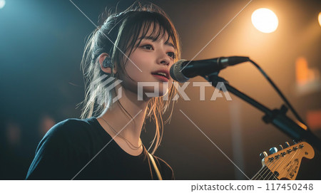 Young female artist singing and playing guitar on stage 117450248