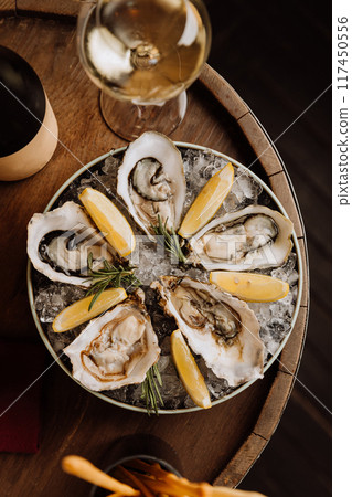 Fresh oysters on ice with lemon wedges and white wine, ideal for gourmet dining and celebrations 117450556