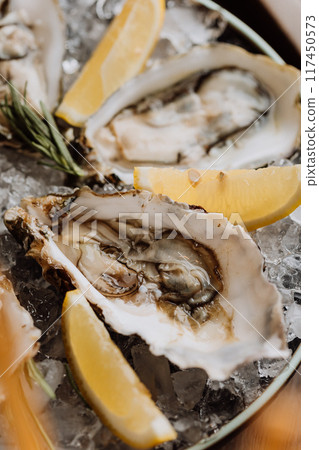 Fresh oysters with lemon on ice, ideal for gourmet seafood dishes and fine dining experiences 117450573