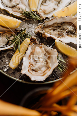 Fresh oysters with lemon on ice, ideal for gourmet seafood dishes and fine dining experiences Fresh oysters with lemon on ice, ideal for gourmet seafood dishes and fine dining experiences 117450574