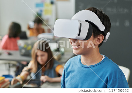 Portrait of smiling young boy wearing VR headset and using immersive technology in school enjoying IT class copy space Portrait of smiling young boy wearing VR headset and using immersive technology in school enjoying IT class copy space 117450962