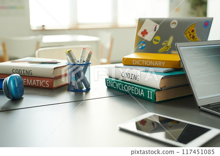 Close up background image of book stack on table in school library with laptop during IT class copy space 117451085