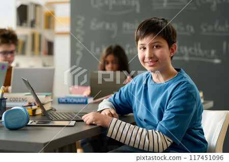 Portrait of teen boy looking at camera in school during computer class for children copy space Portrait of teen boy looking at camera in school during computer class for children copy space 117451096
