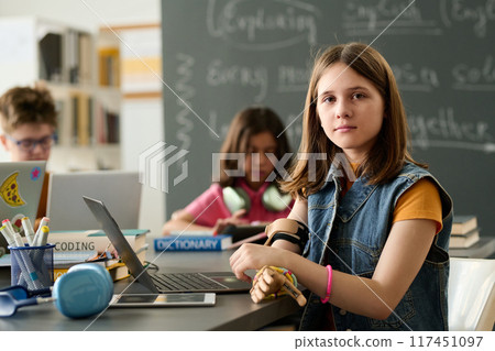 Portrait of teen girl with prosthetic arm using laptop in school library and looking at camera copy space Portrait of teen girl with prosthetic arm using laptop in school library and looking at camera copy space 117451097