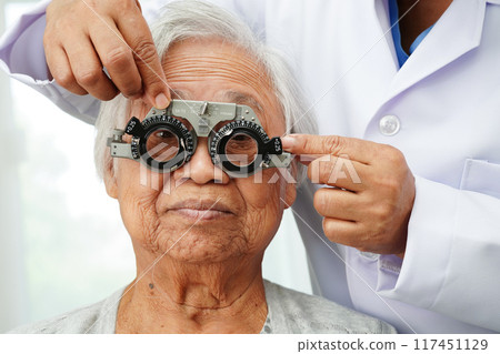 Optometrist checking Asian elderly woman ophthalmic vision eye test and using optical trial frame. Optometrist checking Asian elderly woman ophthalmic vision eye test and using optical trial frame. 117451129