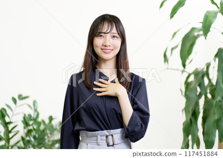 A young woman looking away while holding her hand on her chest 117451884