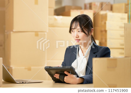 一名年輕女子在倉庫、物流辦公室使用平板電腦工作圖片 117451900