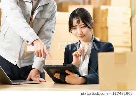 A woman staring at a tablet and a man in work clothes giving instructions Logistics office work image 117451902