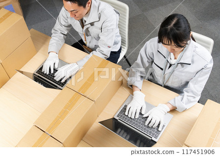 Men and women in work clothes setting up a PC 117451906