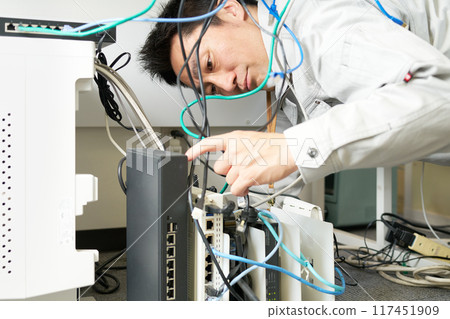 A man in work clothes checking network wiring 117451909