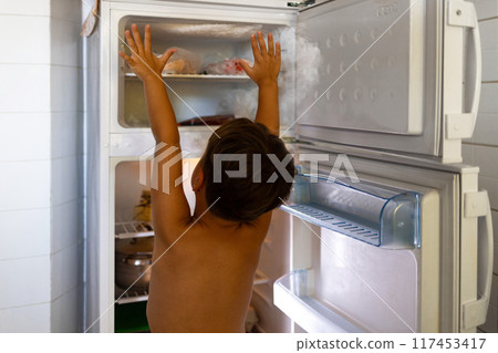 A child takes refuge from the abnormal heat by standing next to an open refrigerator. A child takes refuge from the abnormal heat by standing next to an open refrigerator. 117453417
