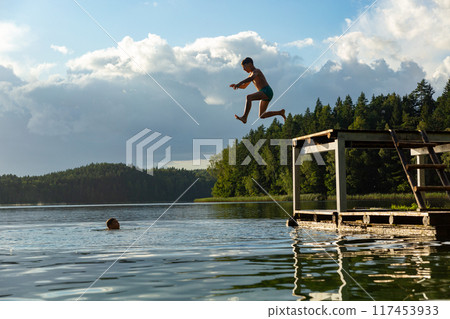 Teenage boys jumping in lake water at summer holiday. 117453933