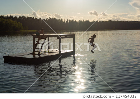 Teenage boys jumping in lake water at summer holiday. Teenage boys jumping in lake water at summer holiday. 117454332