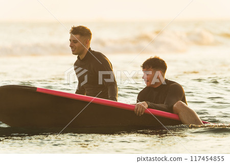 Friends together in the sea with their surfboards Friends together in the sea with their surfboards 117454855