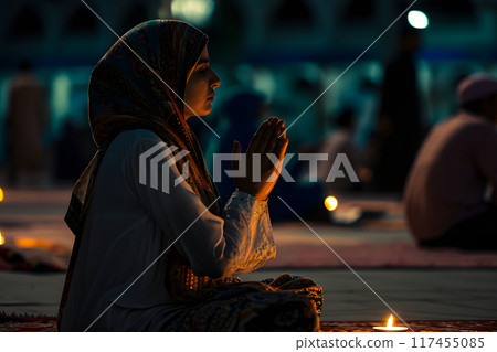 Muslim prayer woman sitting in front of mosque at Ramadan night with selective focus, neural network generated image 117455085