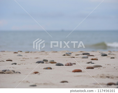 Seascape under a cloudy sky. Skagerrak, Kattegat strait in Skagen, Denmark. Stones on the sand at the foreground Seascape under a cloudy sky. Skagerrak, Kattegat strait in Skagen, Denmark. Stones on the sand at the foreground 117456101