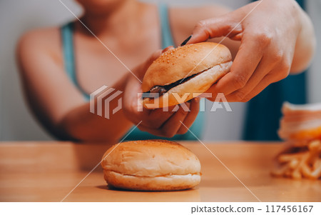 Binge eating disorder concept with woman eating fast food burger, fired chicken , donuts and desserts Binge eating disorder concept with woman eating fast food burger, fired chicken , donuts and desserts 117456167