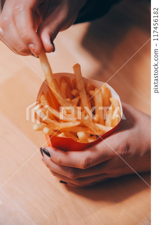 Asian woman holding french fries and eating happily in restaurant 117456182