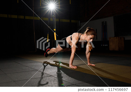 Young woman stretching her body while doing fitness TRX training exercises at gym Young woman stretching her body while doing fitness TRX training exercises at gym 117456697