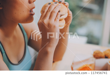 Binge eating disorder concept with woman eating fast food burger, fired chicken , donuts and desserts 117456741