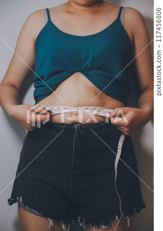 fat woman, fat belly, chubby, obese woman hand holding excessive belly fat with measure tape, woman diet lifestyle concept fat woman, fat belly, chubby, obese woman hand holding excessive belly fat with measure tape, woman diet lifestyle concept 117456806