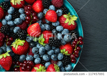 Mix of ripe colorful berries in bowl photography . Blueberry , strawberry , raspberry , blackberry and red currant . Top view 117457891