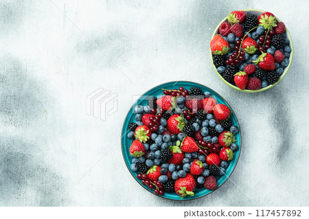 Mix of ripe colorful berries in bowl photography . Blueberry , strawberry , raspberry , blackberry and red currant . Top view 117457892