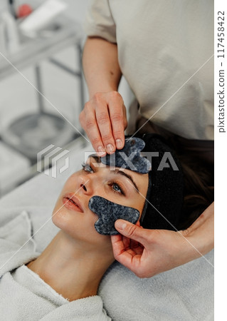 Professional facial treatment with gua sha technique in spa during relaxing afternoon session Professional facial treatment with gua sha technique in spa during relaxing afternoon session 117458422
