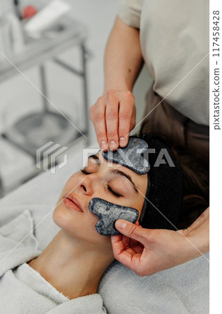 Relaxing facial treatment with gua sha at a spa during a serene afternoon 117458428