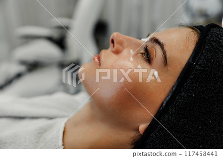 Woman receiving skincare treatment in spa setting during afternoon relaxation session 117458441