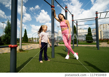 Mother and daughter enjoying fitness together at a park on a sunny day Mother and daughter enjoying fitness together at a park on a sunny day 117458469