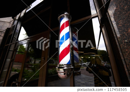 Traditional barber pole displayed outside a barber shop during the day Traditional barber pole displayed outside a barber shop during the day 117458505