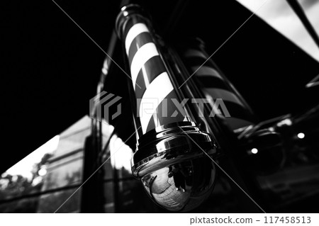 Barber pole in black and white, showcasing traditional design outside a barber shop on a sunny day Barber pole in black and white, showcasing traditional design outside a barber shop on a sunny day 117458513