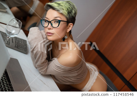 A beautiful girl with short hair in her underwear is sitting sexy in a room at a laptop, working and chatting online A beautiful girl with short hair in her underwear is sitting sexy in a room at a laptop, working and chatting online 117458546