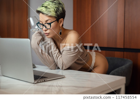 A beautiful girl with short hair in her underwear is sitting sexy in a room at a laptop, working and chatting online 117458554