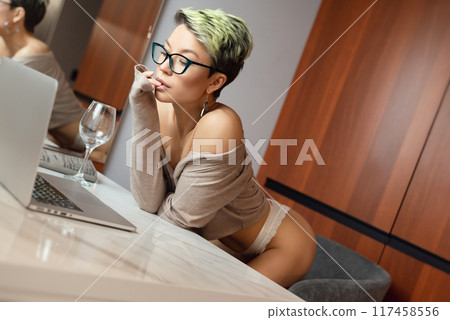 A beautiful girl with short hair in her underwear is sitting sexy in a room at a laptop, working and chatting online 117458556