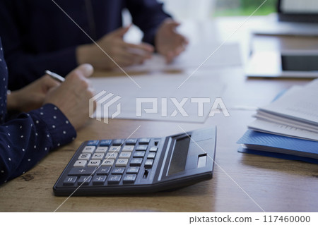 Accountants or auditors are discussing review of financial documents while sitting at the wooden desk in office. Professionals analyzing paper reports and using calculator and tablet computer, close Accountants or auditors are discussing review of financial documents while sitting at the wooden desk in office. Professionals analyzing paper reports and using calculator and tablet computer, close 117460000