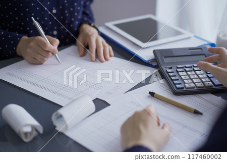 Female accountants or auditors reviewing financial data in office. Professionals analyzing paper reports and using calculator, close up view. Audit and taxes in business Female accountants or auditors reviewing financial data in office. Professionals analyzing paper reports and using calculator, close up view. Audit and taxes in business 117460002