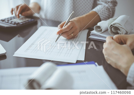 Woman accountant using a calculator and laptop computer while counting taxes for a client. Business audit and finance concepts Woman accountant using a calculator and laptop computer while counting taxes for a client. Business audit and finance concepts 117460098