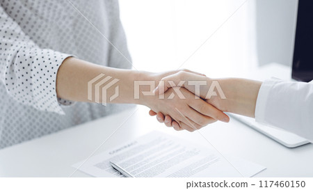 Business people shaking hands above contract papers just signed on the white table, closeup. Lawyers at meeting. Teamwork, partnership, success concept 117460150