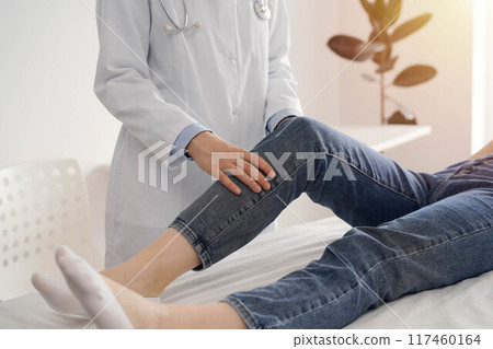 Doctor and patient are at the medical inspection in clinic. Orthopedic examines the knee of a young woman. Medicine concept Doctor and patient are at the medical inspection in clinic. Orthopedic examines the knee of a young woman. Medicine concept 117460164