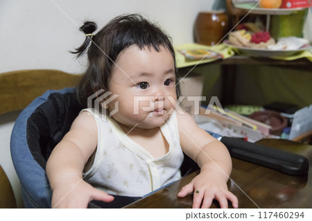 [Baby with tied hair eating baby food] 117460294