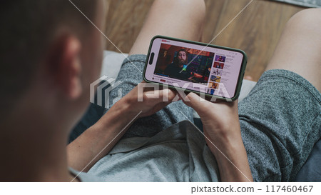 Caucasian boy watches video of blogger about stock trading using phone 117460467