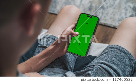 Teenage boy uses mobile phone with green screen mockup Teenage boy uses mobile phone with green screen mockup 117460522