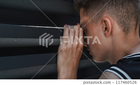 Caucasian teenager peeking through gap between the iron fence Caucasian teenager peeking through gap between the iron fence 117460526