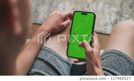 Teenage boy uses mobile phone with green screen mockup 117460527