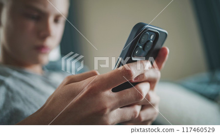 Close up of teenage boy typing and chatting using mobile phone Close up of teenage boy typing and chatting using mobile phone 117460529