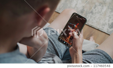 Teen boy scrolls through and watches social network feed with short videos using phone Teen boy scrolls through and watches social network feed with short videos using phone 117460548
